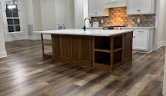 A kitchen with white counters and cabinets, a wood island and wood floor after a move out clean.