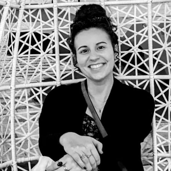 Smiling woman with curly hair in a patterned chair.