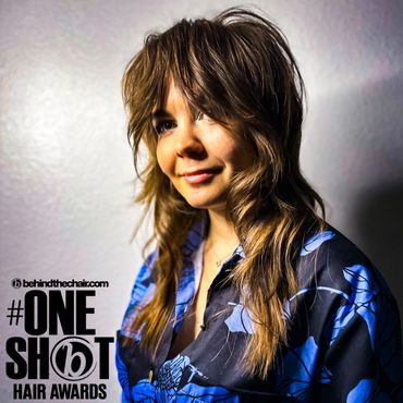 Woman with layered haircut and floral shirt posing for hair awards photo.