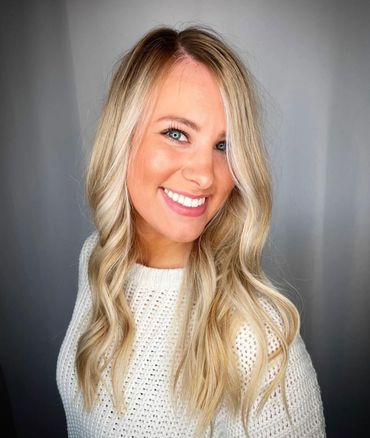 Smiling woman with long blonde hair and blue eyes in a white knit sweater.