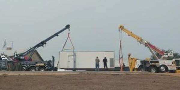 Two cranes setting a large Industrial Generator with workers supervision..