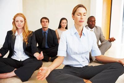 Business professionals meditating together in a calm, indoor setting.