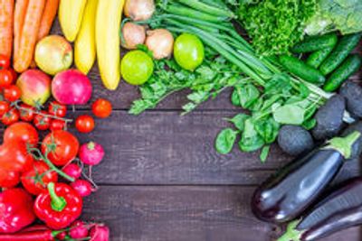 Colorful fresh fruits and vegetables arranged on a wooden surface.