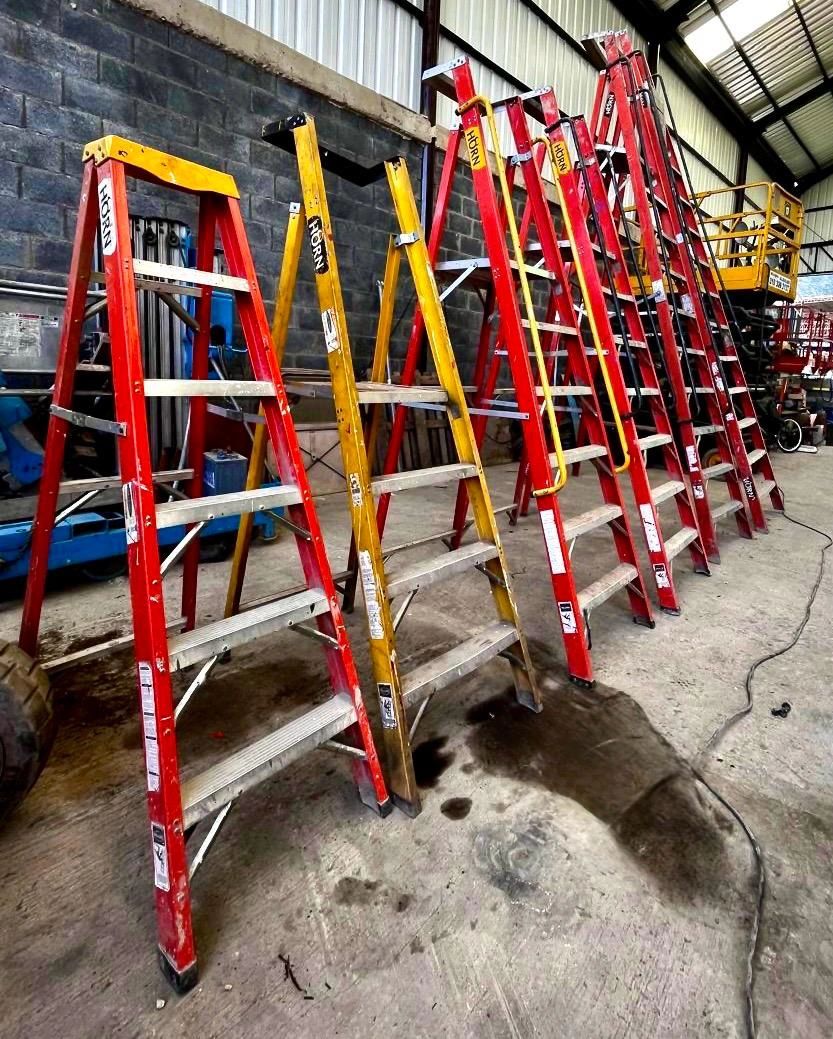 Escaleras de varios colores alineadas en un taller.