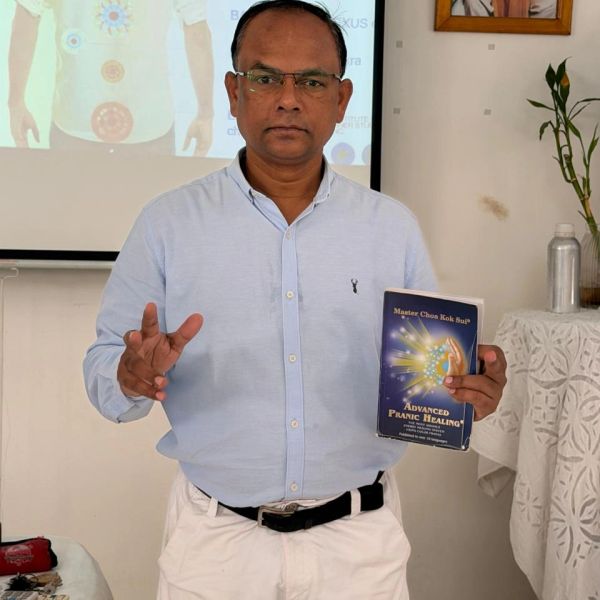 Man presenting a book on advanced pranic healing during a seminar.