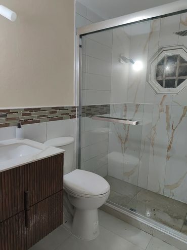 Modern bathroom with a glass shower enclosure and wood-textured vanity.