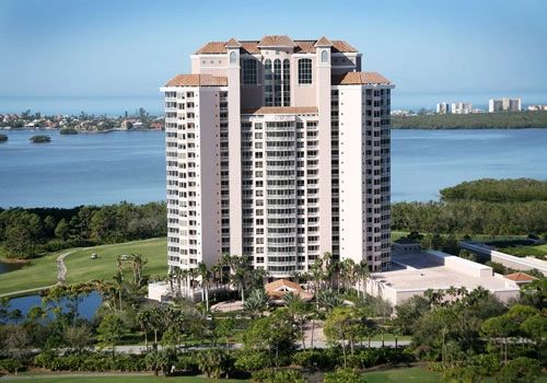 Tall residential building near water and greenery.
