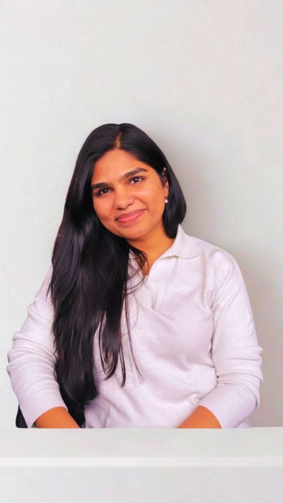 A woman with long dark hair and a white shirt smiling gently.