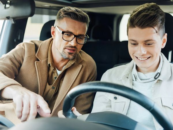 A trainer training the teen about the car