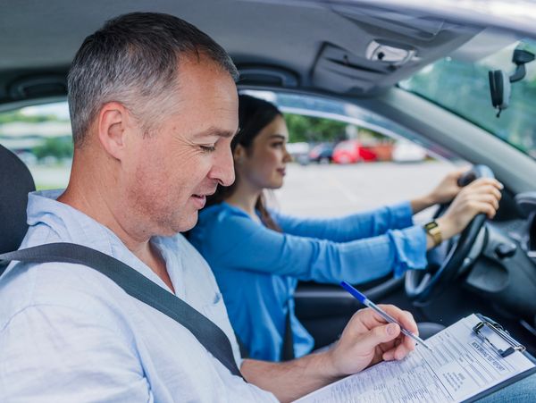 A trainer sitting in the car and writing on a document