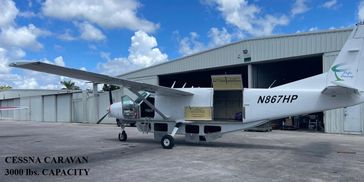 A white Cessna Caravan aircraft, marked with "N867HP", parked outdoors with its cargo door open.