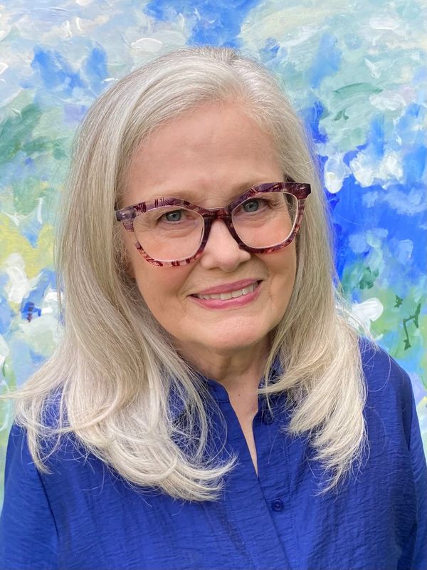 Smiling elderly woman with white hair and glasses.