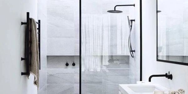 Modern minimalist bathroom with glass shower and black fixtures.
