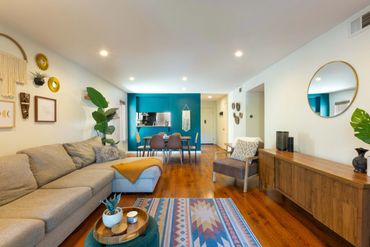 Cozy modern living room with teal accent wall and wooden furniture.