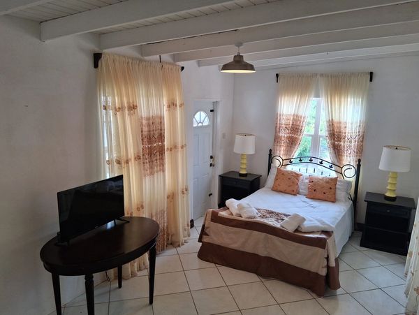 Cozy bedroom with a double bed, matching curtains, and a TV on a wooden table.