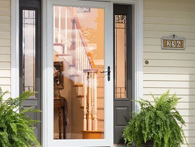 A white storm door with a glass panel and brass doorknob displayed for a home improvement store