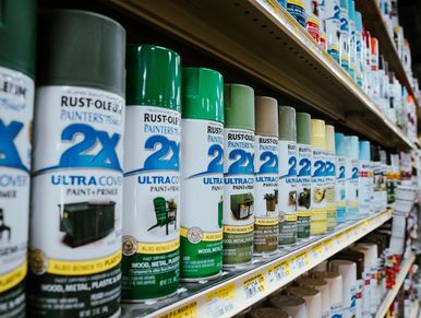 Paint in various colors displayed for sale on a wooden counter at a local hardware store