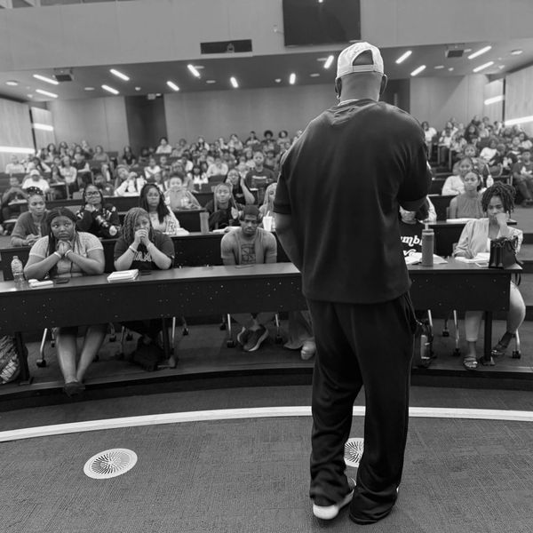 A speaker addressing a large audience in a lecture hall.