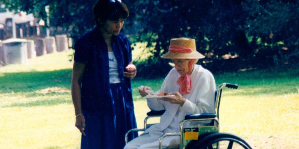 Resident eating food in a park with a caregiver