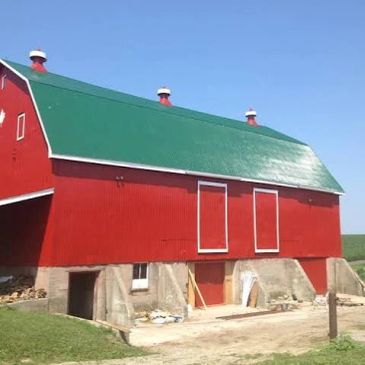 Red barn with green roof under clear sky.