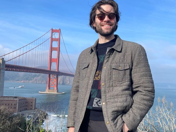 Man smiling near the Golden Gate Bridge on a sunny day.