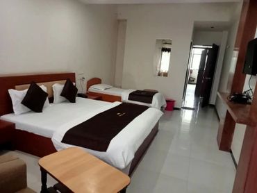 Minimalist hotel room with two beds and a small table.