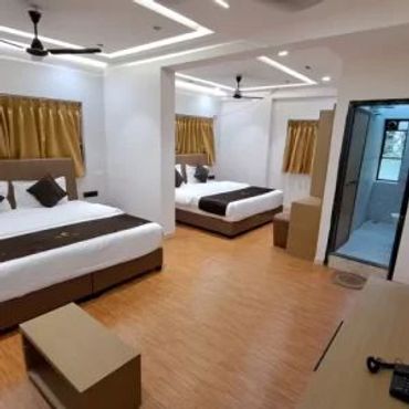 A modern hotel room with two beds and wooden flooring.