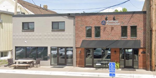 Two connected commercial buildings with outdoor seating on a street.