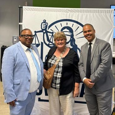 Three people posing for a photo in front of a legal-themed backdrop.