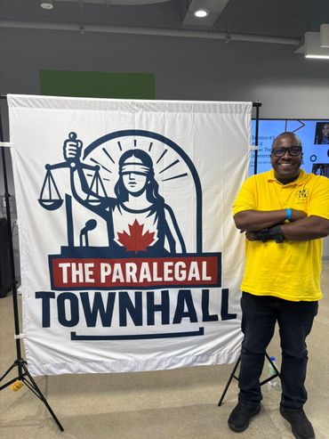 A smiling man in a yellow shirt stands next to a banner for The Paralegal Townhall.