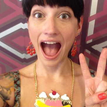 Woman excitedly posing with peace sign and colorful dessert necklace.