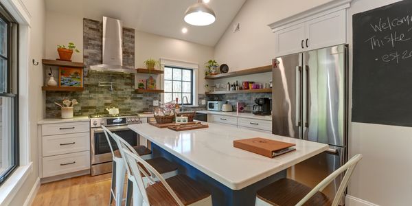 Modern kitchen with white cabinetry, wooden shelves, and a large island with bar stools.