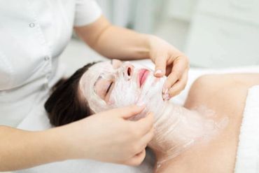 Skin care technician doing facial treatment .