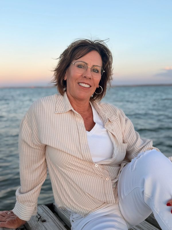 Woman smiling by the water at sunset.