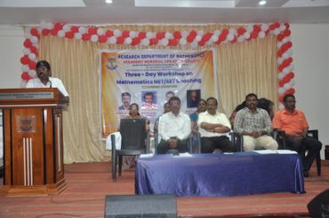A speaker addresses attendees at a mathematics workshop in a decorated auditorium.