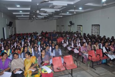 A large group of students seated in a classroom or seminar hall attentively listening.