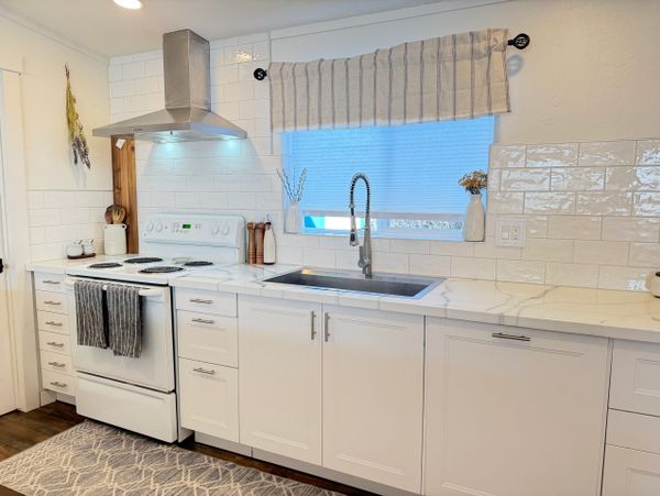 Bright modern kitchen with white cabinets and stainless steel hood.