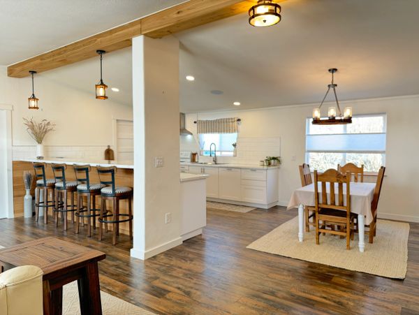 Modern open kitchen with wooden floors and a dining area.