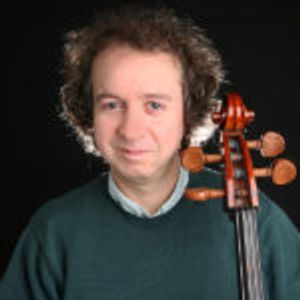 Man smiling at camera holding a cello