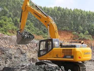 A yellow excavator with its bucket lowered, digging into a rocky hillside