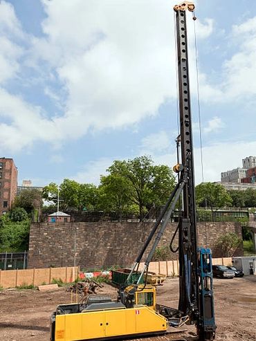 A parked yellow mobile crane, seen from the side, on a paved surface.