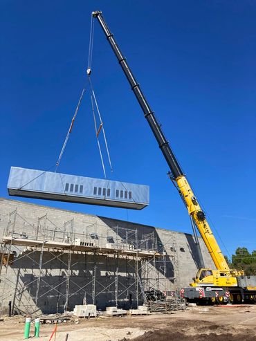 A large yellow crane with a vertical drilling arm at a construction site.
