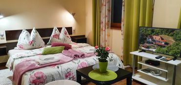 Cozy bedroom with floral bedding and a TV showing a house.
