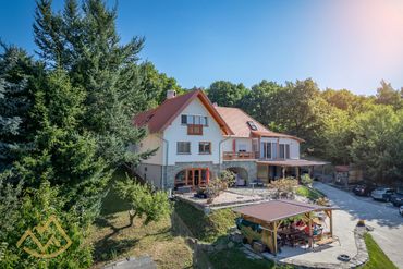 Large countryside house with outdoor seating area and lush greenery.