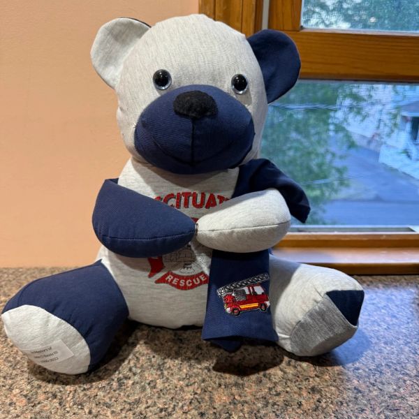 Stuffed bear wearing a scarf with a fire truck design.