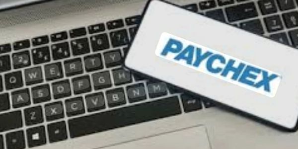 Smartphone displaying Paychex logo on a laptop keyboard.