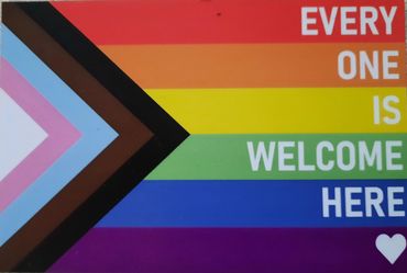 Progress Pride flag with the caption "EVERYONE IS WELCOME HERE", ending with the heart symbol.