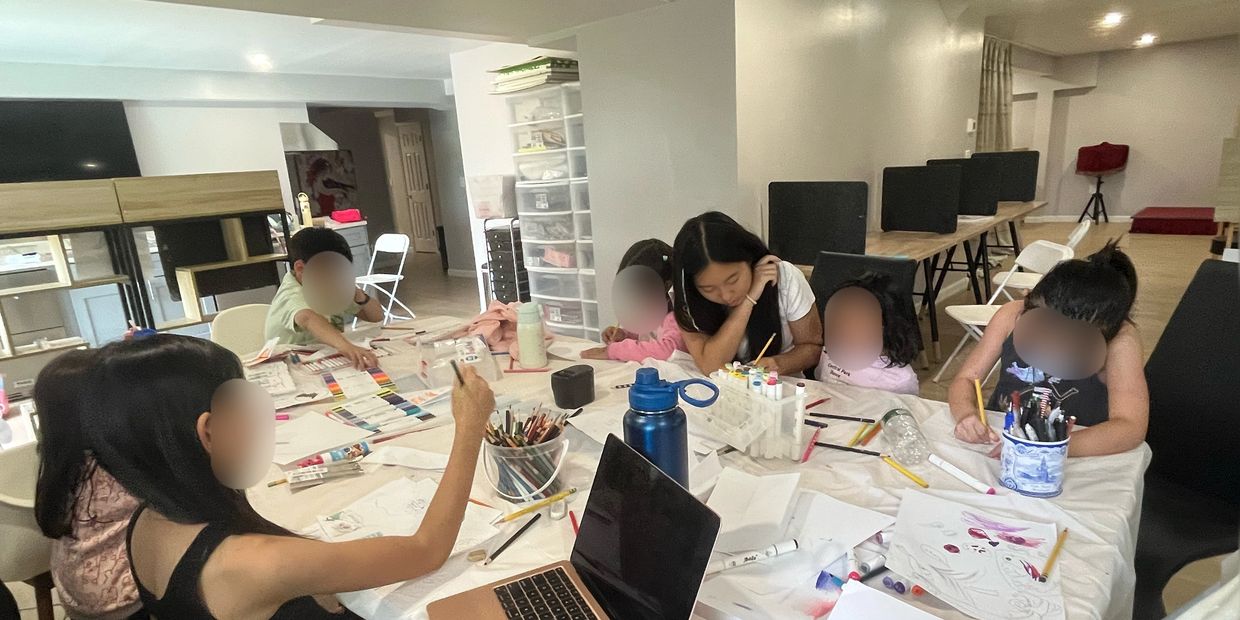 Children and adults engaged in a group art activity with paints and pencils.