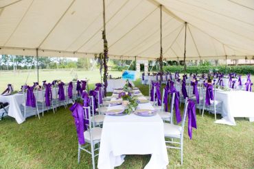 Elegant outdoor event setup with purple decorations.