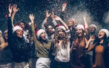 Group celebrating Christmas with Santa hats in falling snow.